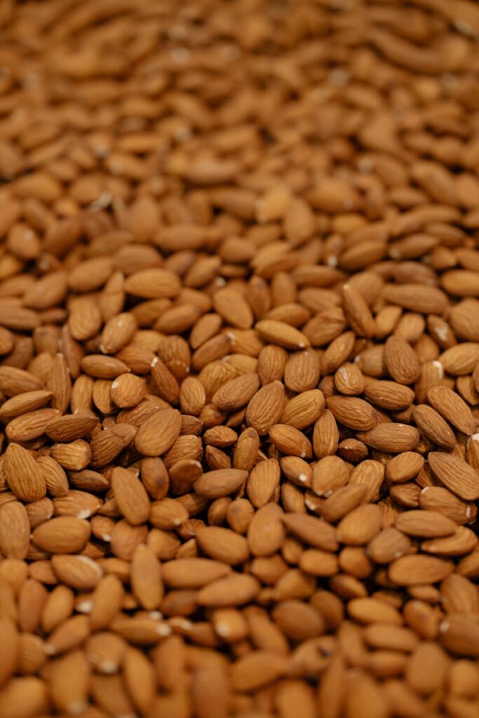 A detailed close-up of a large batch of raw almonds, emphasizing texture and natural detail.